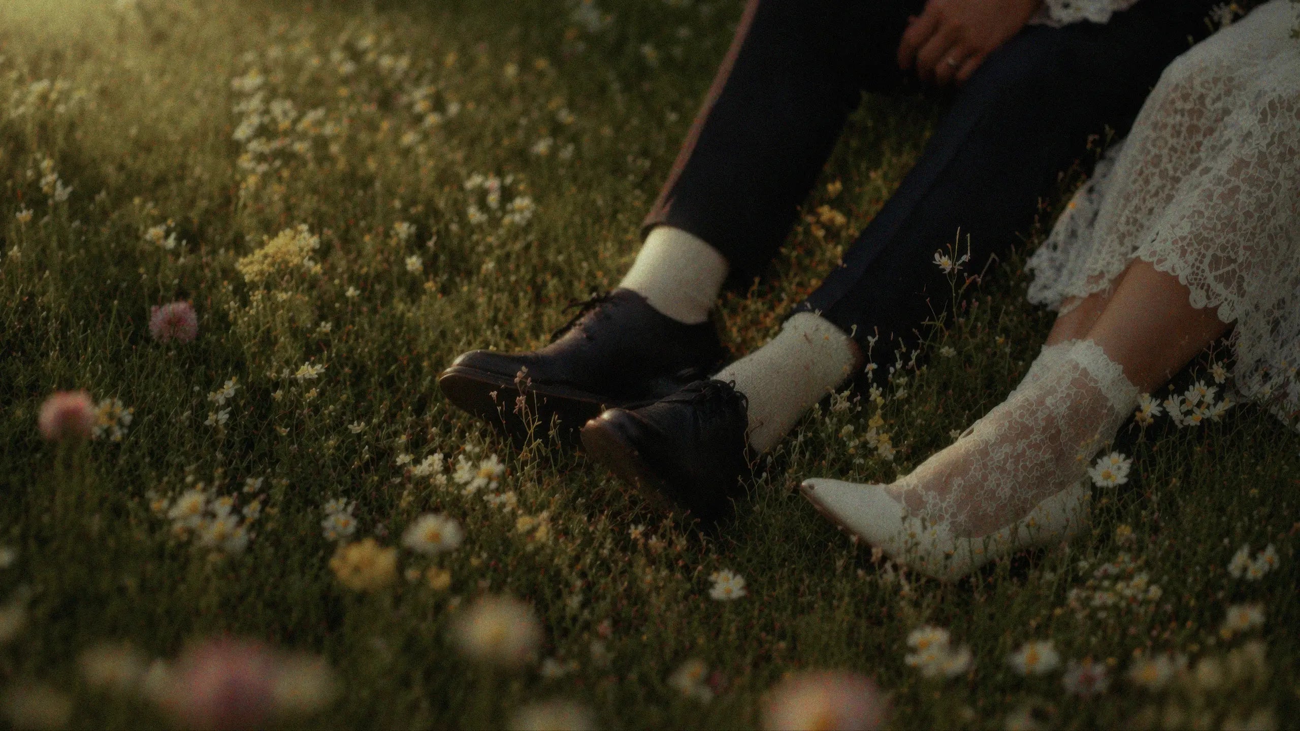 Romantic wedding couple sitting in wildflower meadow, soft cinematic garden aesthetic for wedding website templates
