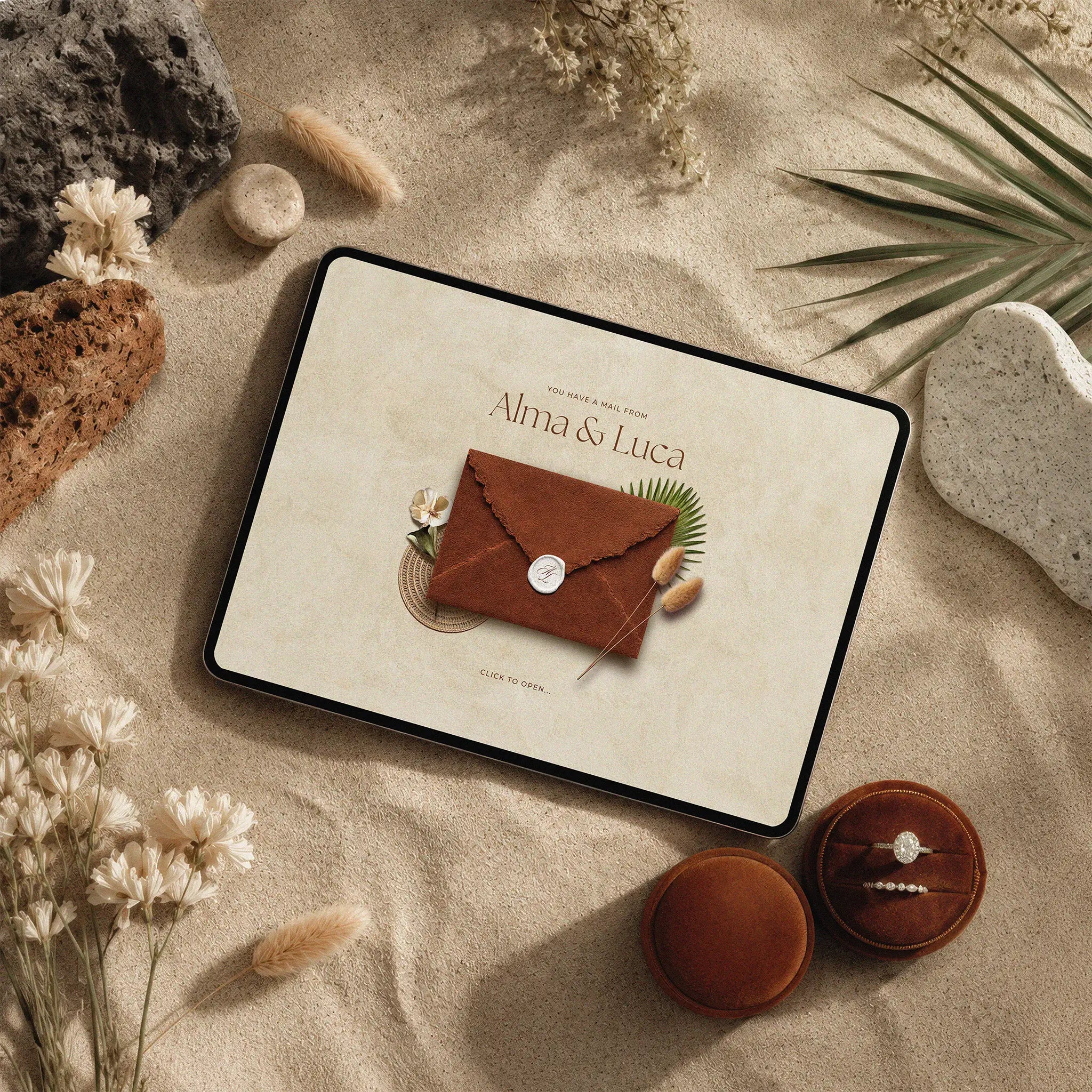 Sunset terracotta wedding website template shown on iPad, brown suede envelope with wax seal on desert sand